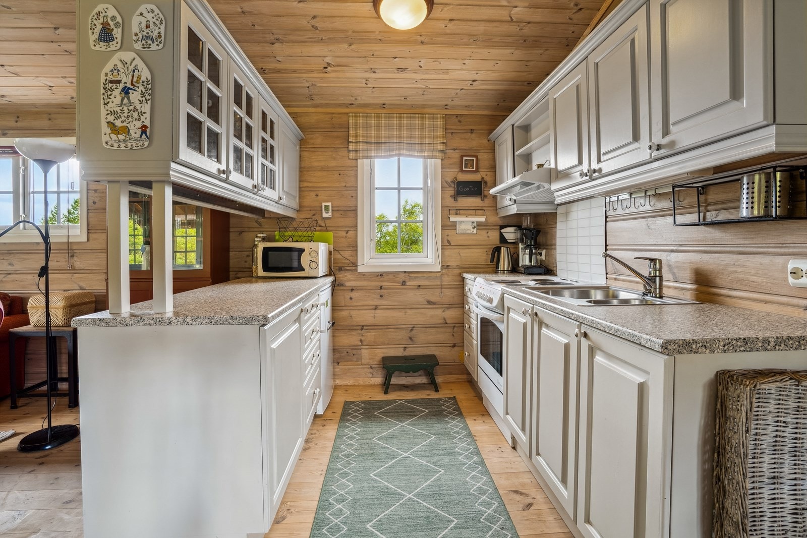 Kjøkkeninnredning med komfyr med avtrekksvifte, kjøleskap og stålkum Galleribilde