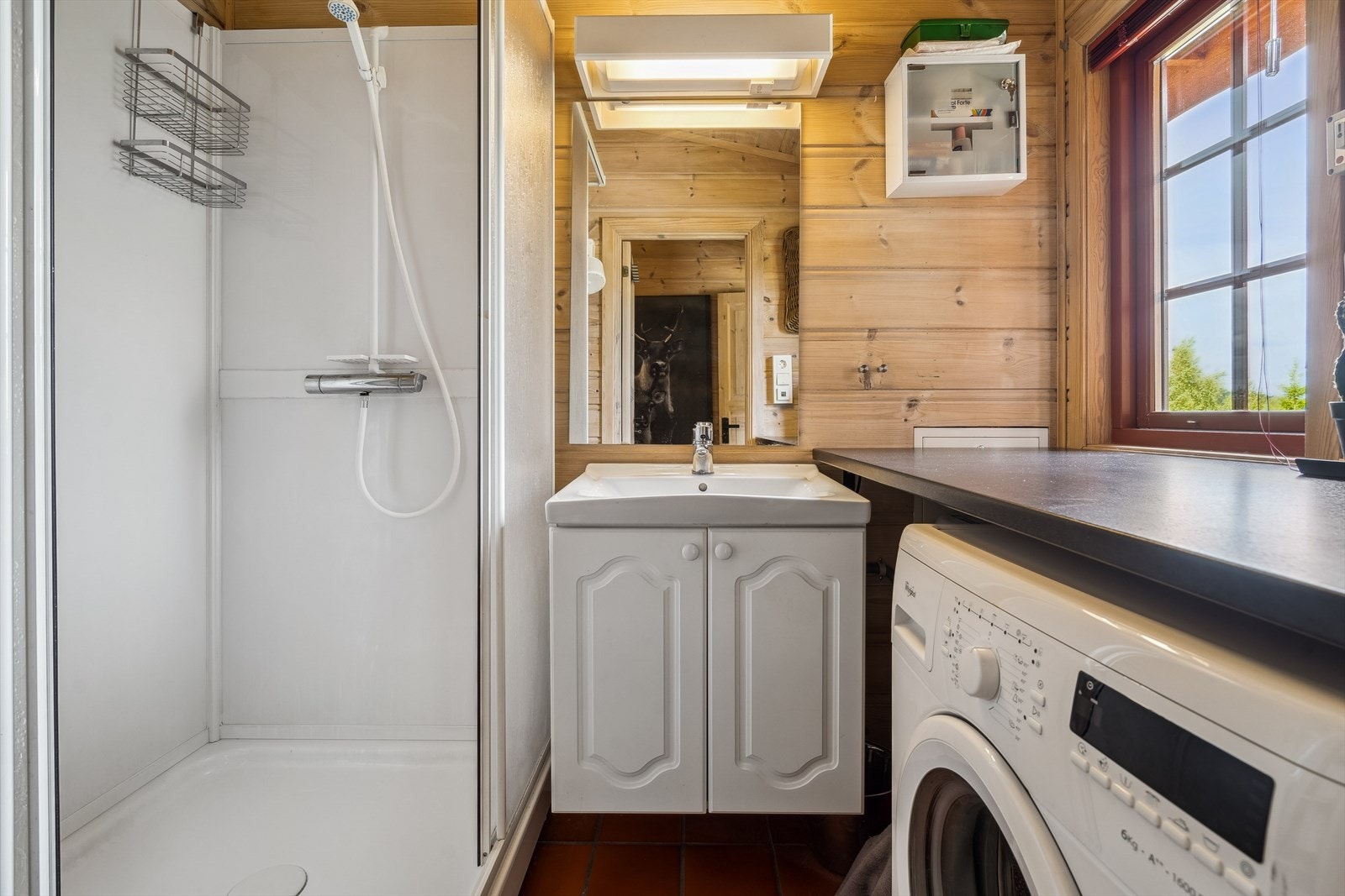 Badet er utstyrt dusjkabinett, servant med underskap og opplegg for vaskemaskin Galleribilde