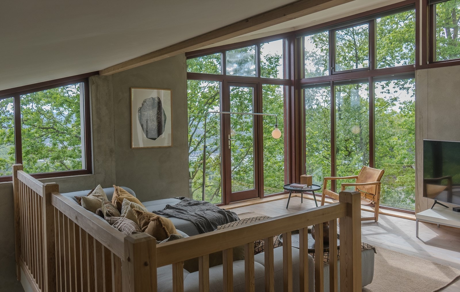 Lys og luftig stue med store vindusflater og vakker utsikt mot skogen, gir en følelse av å være tett på naturen. Galleribilde