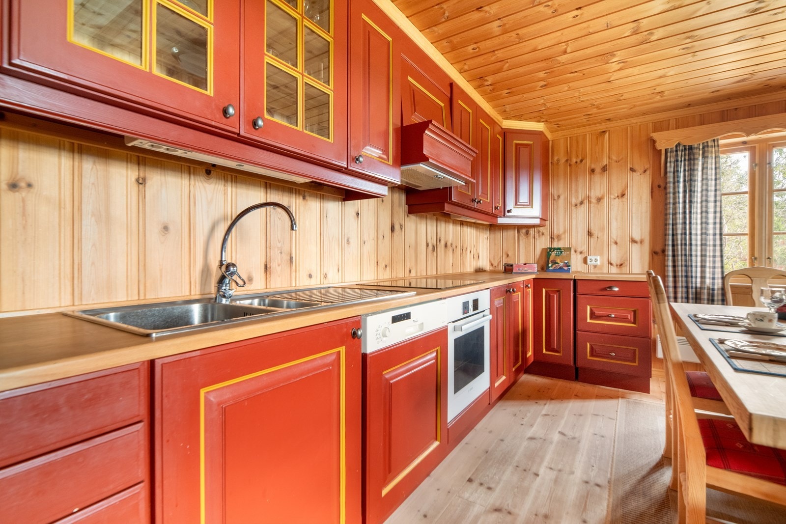 God oppbevaringsplass i heltre, malt innredning fra 2004 med takhøye overskap og innslag av glass-skap. Over kokesonen er det ventilator med avtrekk ut til yttervegg. Galleribilde