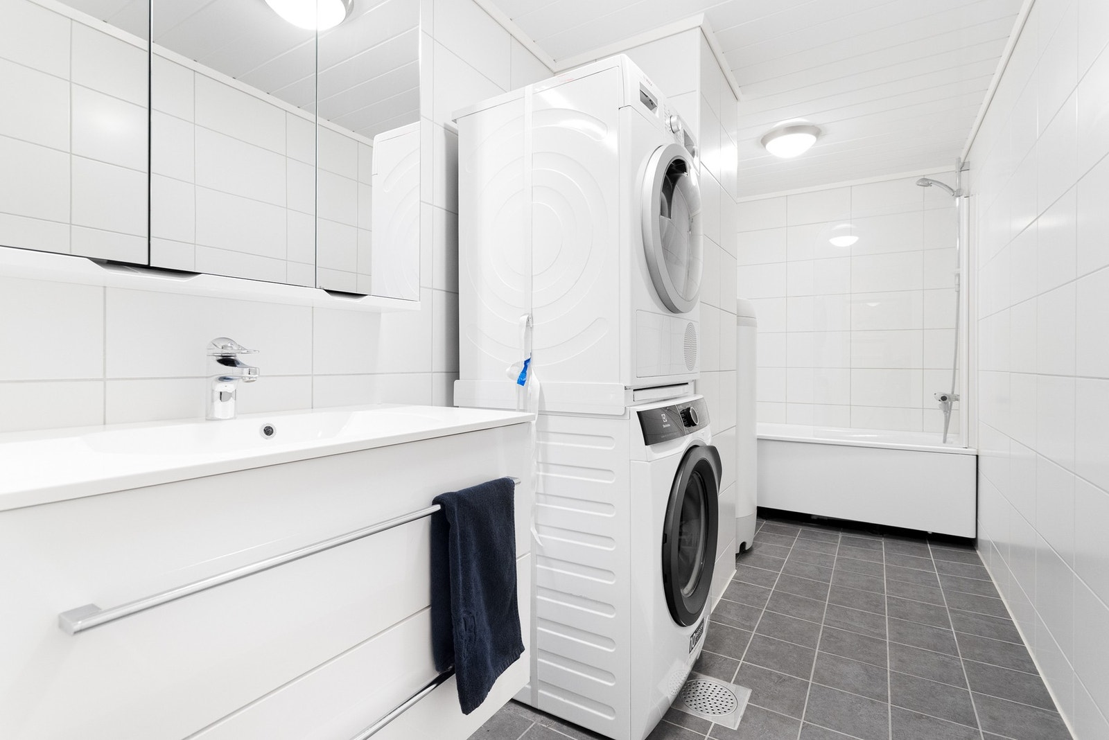 Innredet med badekar, baderomsinnredning med vask og opplegg for vaskemaskin. Galleribilde