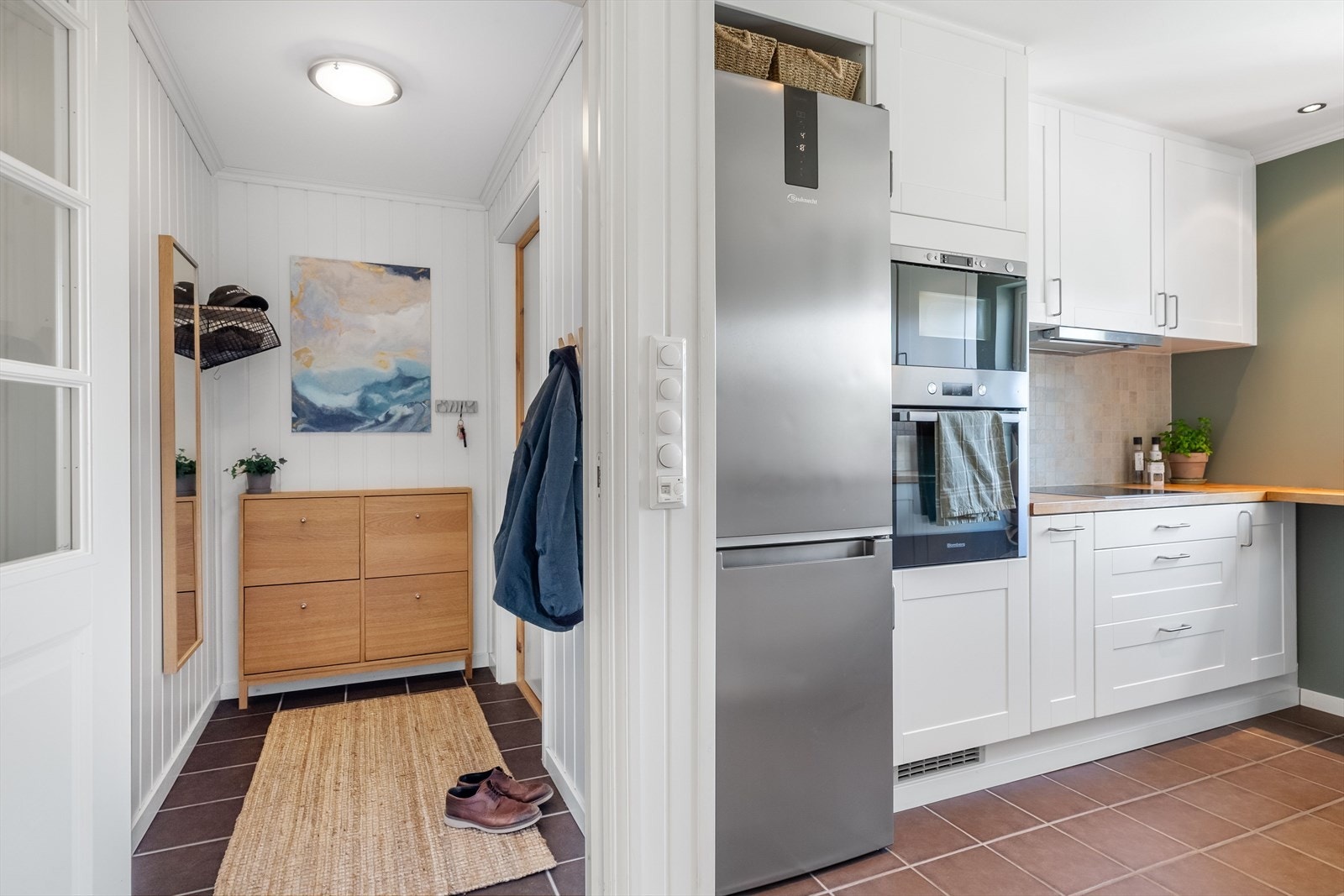 Lys og innbydende entré med klesoppheng for yttertøy og lagring av skotøy. Kjøkkenet finnet man på venstre hånd i det man entrer boligen. Galleribilde