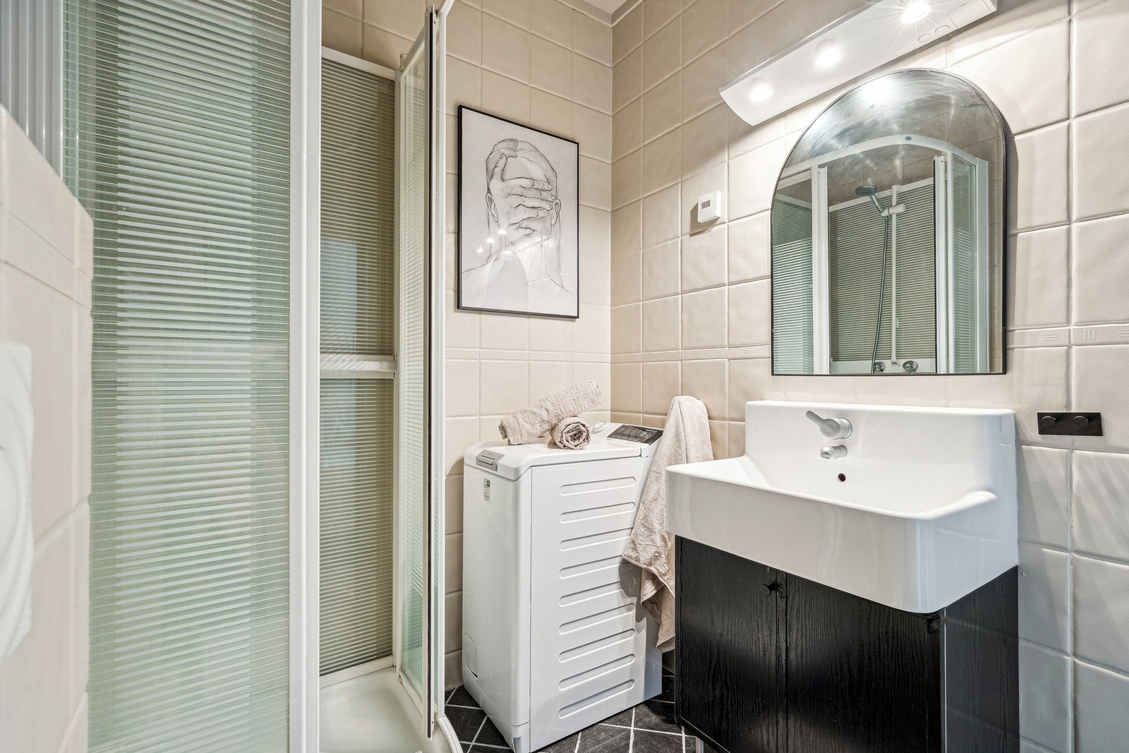 Badet er utstyrt med en vegghengt servantinnredning, samt speil med overlys og stikkontakt, som gir både god belysning og funksjonalitet. Videre har badet et praktisk dusjkabinett og et plassbesparende vegghengt toalett, som gir et moderne og ryddig uttry Galleribilde