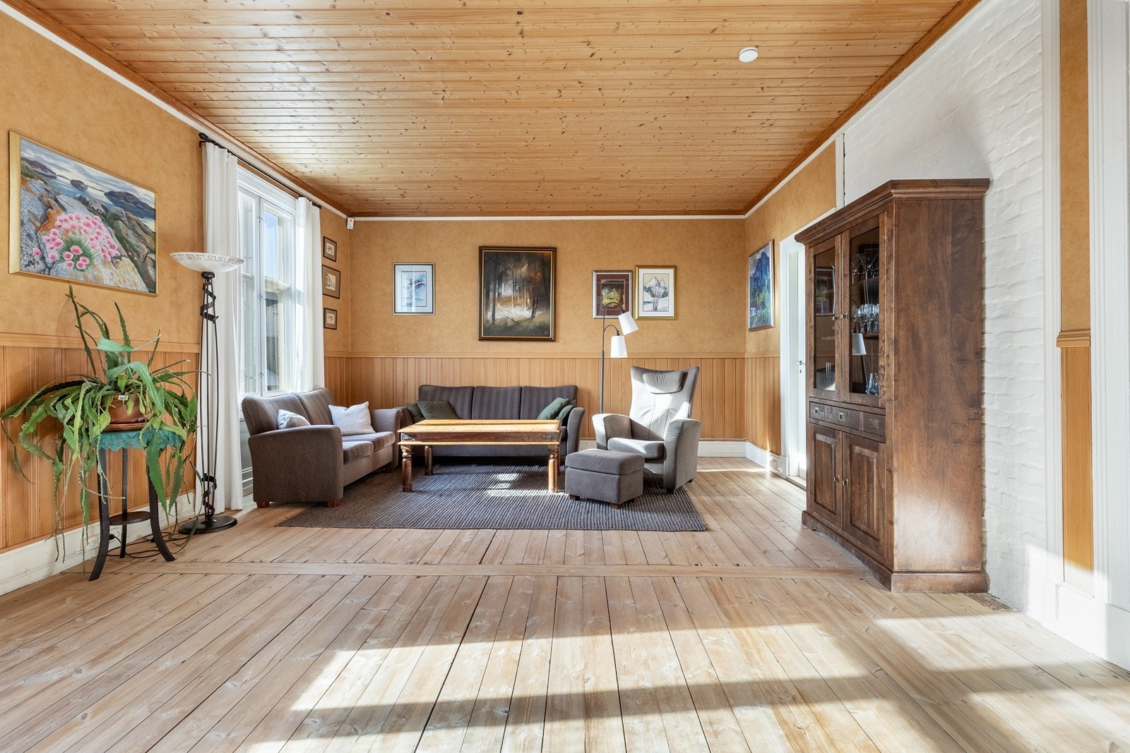Romslig dagligstue med brystpanel og tapetserte vegger. Godt med vinduer slipper inn naturlig lys og sørger for fint utsyn til den flotte utsikten Galleribilde