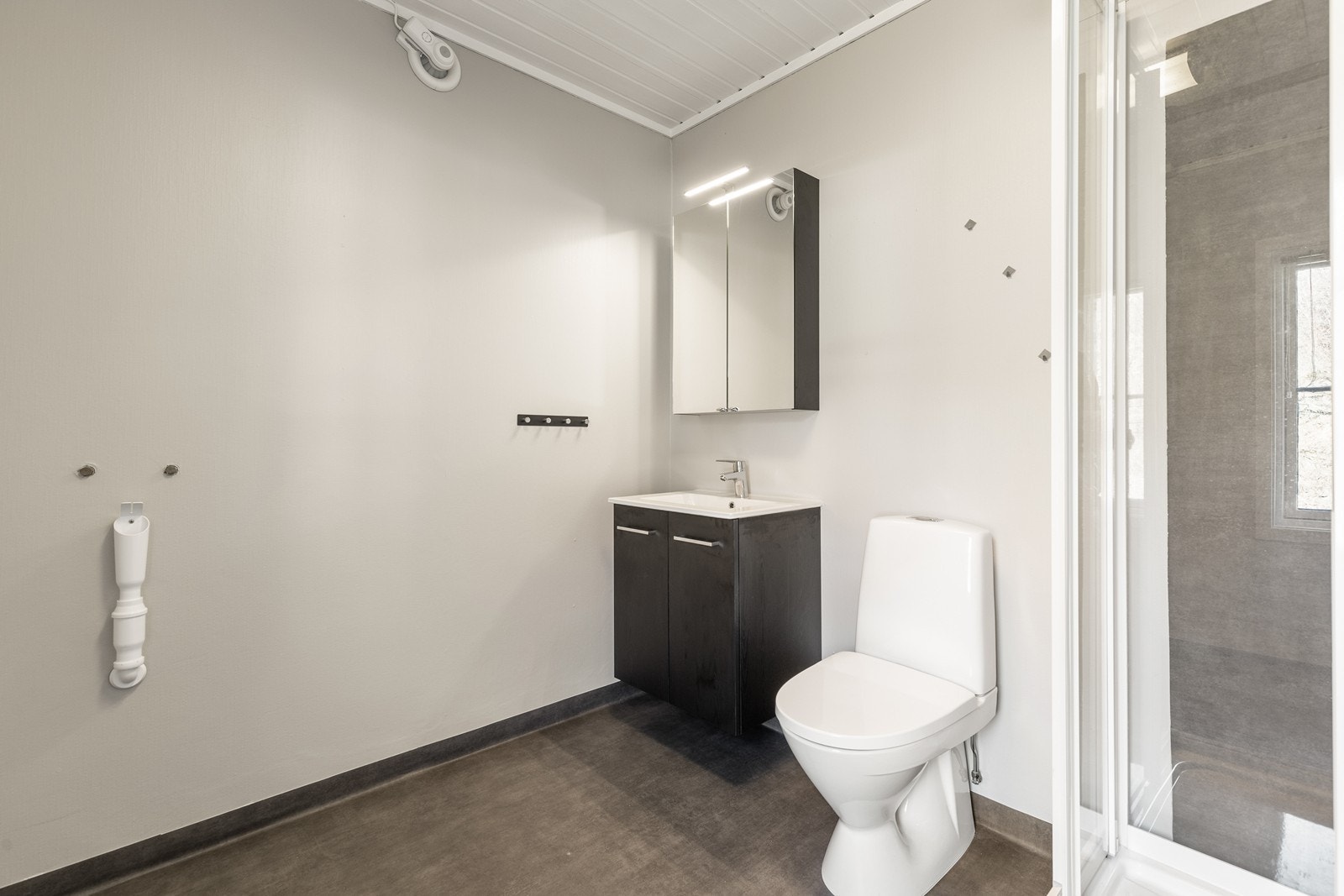 Badet i hybel har dusjkabinett, wc og baderomsmøbel. Opplegg for vaskemaskin Galleribilde