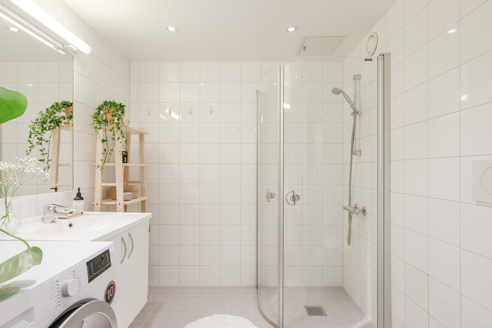 Tidløst bad, i god størrelse. Badet er utstyrt med åpen dusj med dusjvegger i herdet glass, toalett med skjult sisterne, skapinnredning med helstøpt servant og opplegg for vaskemaskin. Galleribilde