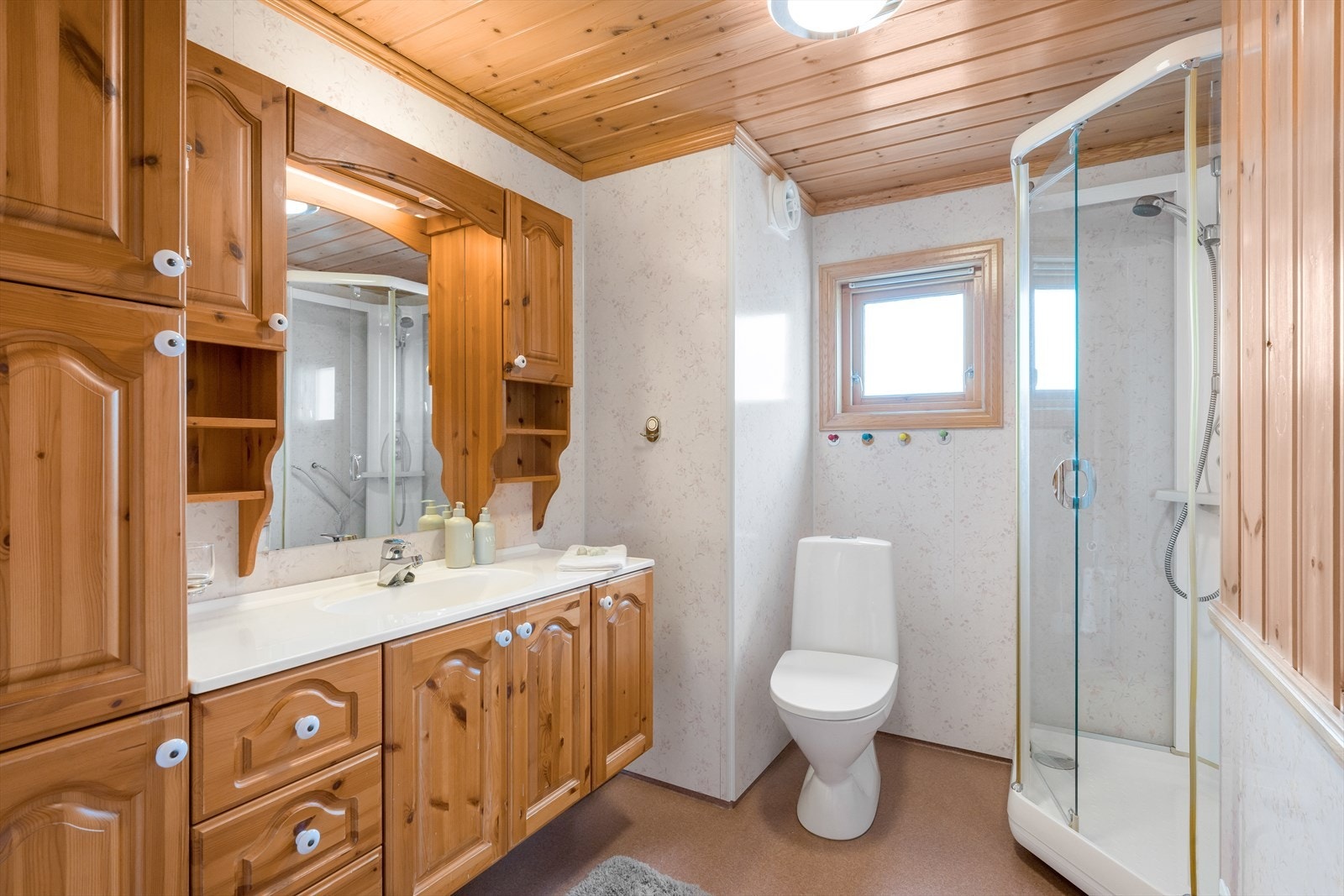 Pent baderom med stor baderomsinnredning hvor en har rikelig med oppbevaring. Dusjkabinett. Galleribilde