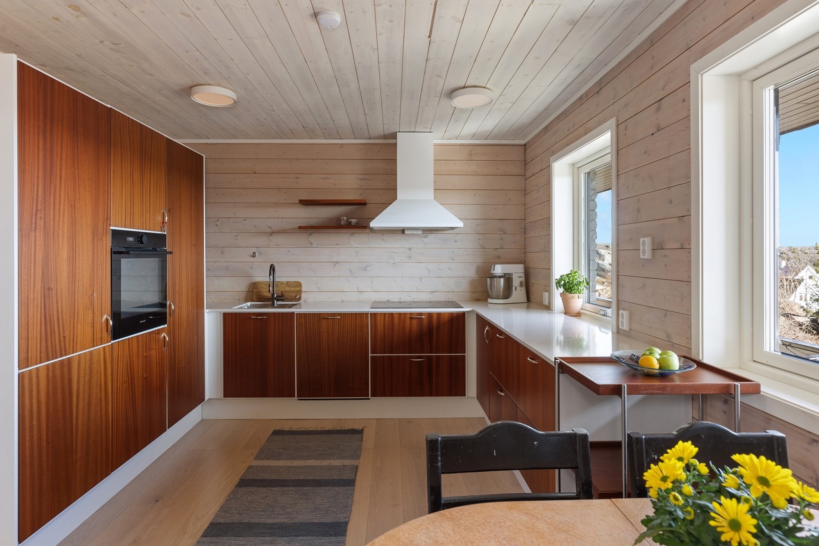 Kjøkkenet har innredning med glatte fronter og benkeplate av kompositt med stål oppvask-kum Galleribilde