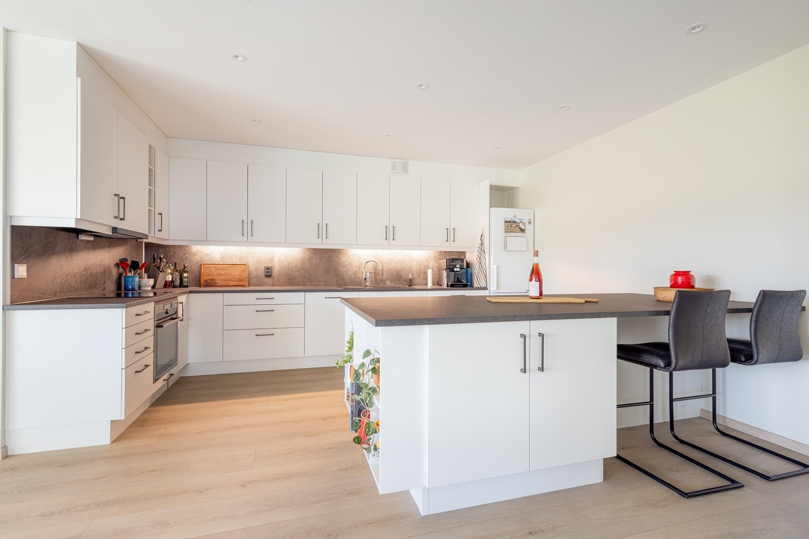 Velutstyrt og romslig kjøkken med gode arbeidsflater hvor deler av innredningen består av en fin kjøkkenøy som også deler av rommet mot stuen. Galleribilde