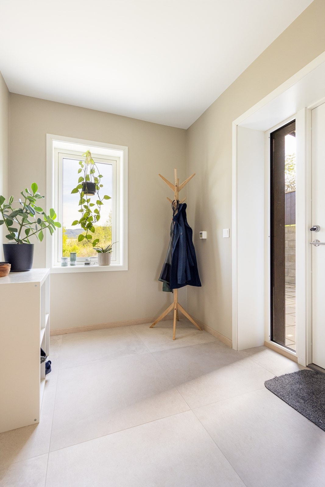 En lys entré ønsker deg velkommen inn i boligen hvor det er flis på gulv med gulvvarme. Galleribilde