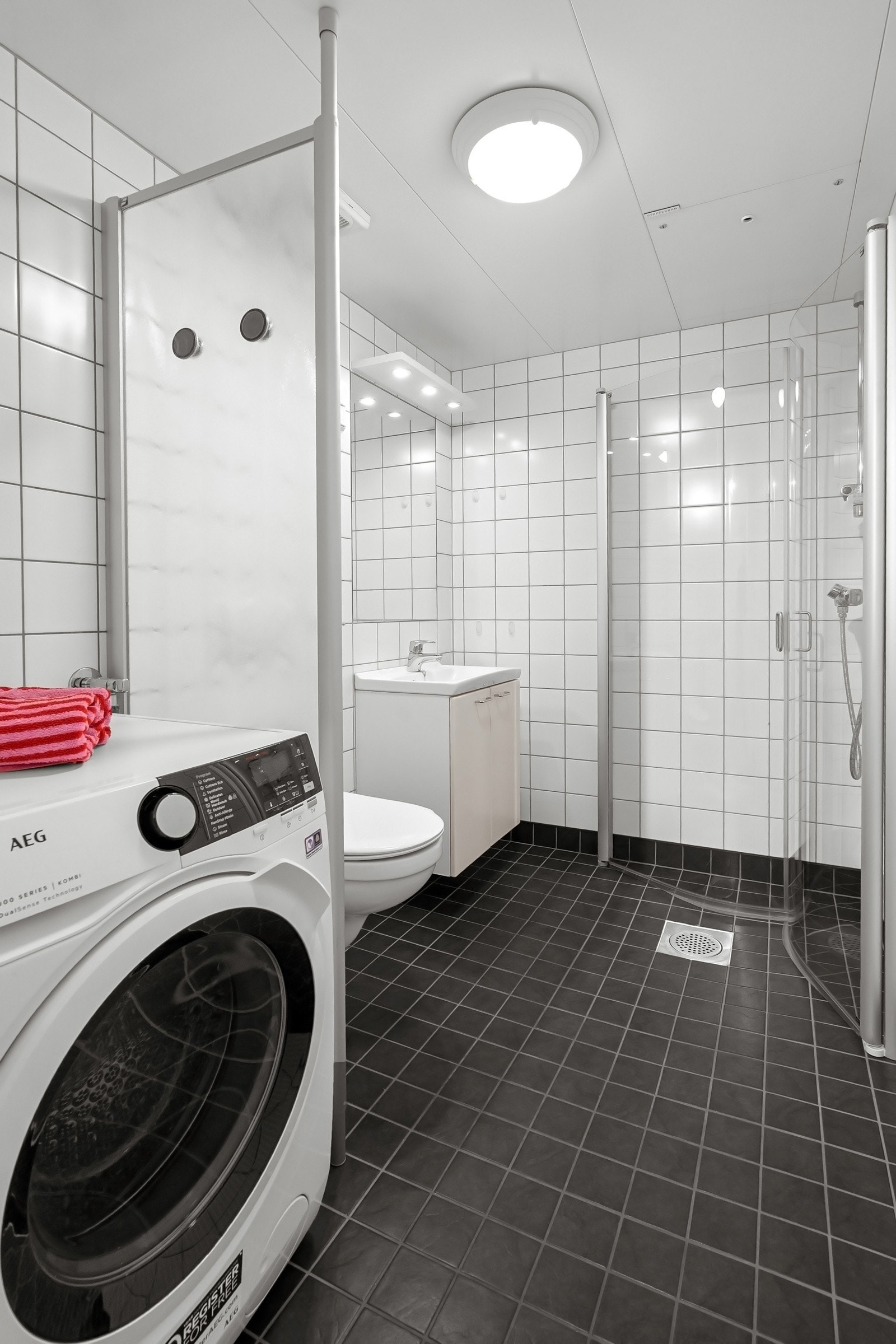 Rommet er utstyrt med servant med innredning, vegghengt toalett og dusjhjørne med glassdører. Det er opplegg for vaskemaskin og en AEG vaskemaskin/tørketrommel (9 kg vask og 5 kg tørk) følger ved salg. Galleribilde