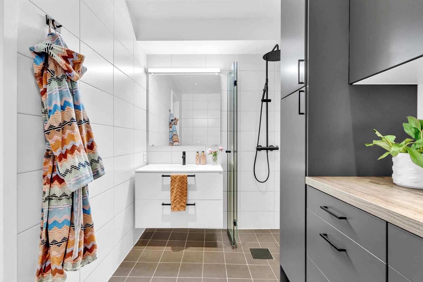 Det er videre innredet med nedfelt servant med underskuffer og 1-greps blandebatteri, dusjhjørne med glassdører, vegghengt toalett og opplegg for vaskemaskin. Galleribilde