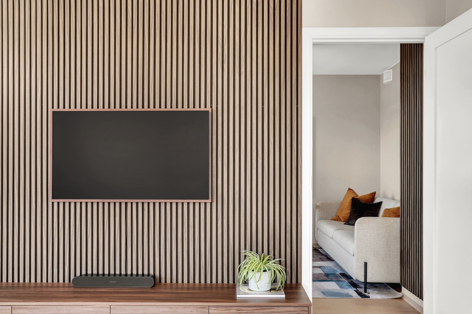 Stuen har en moderne spilevegg (premium dobbel isolasjon) i mørkt tre og en skreddersydd TV-reol for en elegant finish. Galleribilde