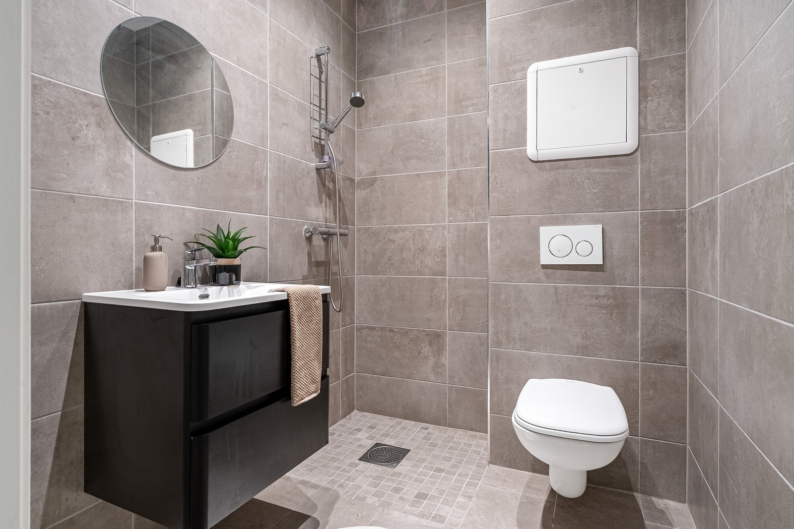 Meget pent flislagt bad med gulvvarme, downlights i himling og opplegg for vaskemaskin. Videre er badet innredet med servantskap med speil, vegghengt toalett og dusjhjørne. Galleribilde