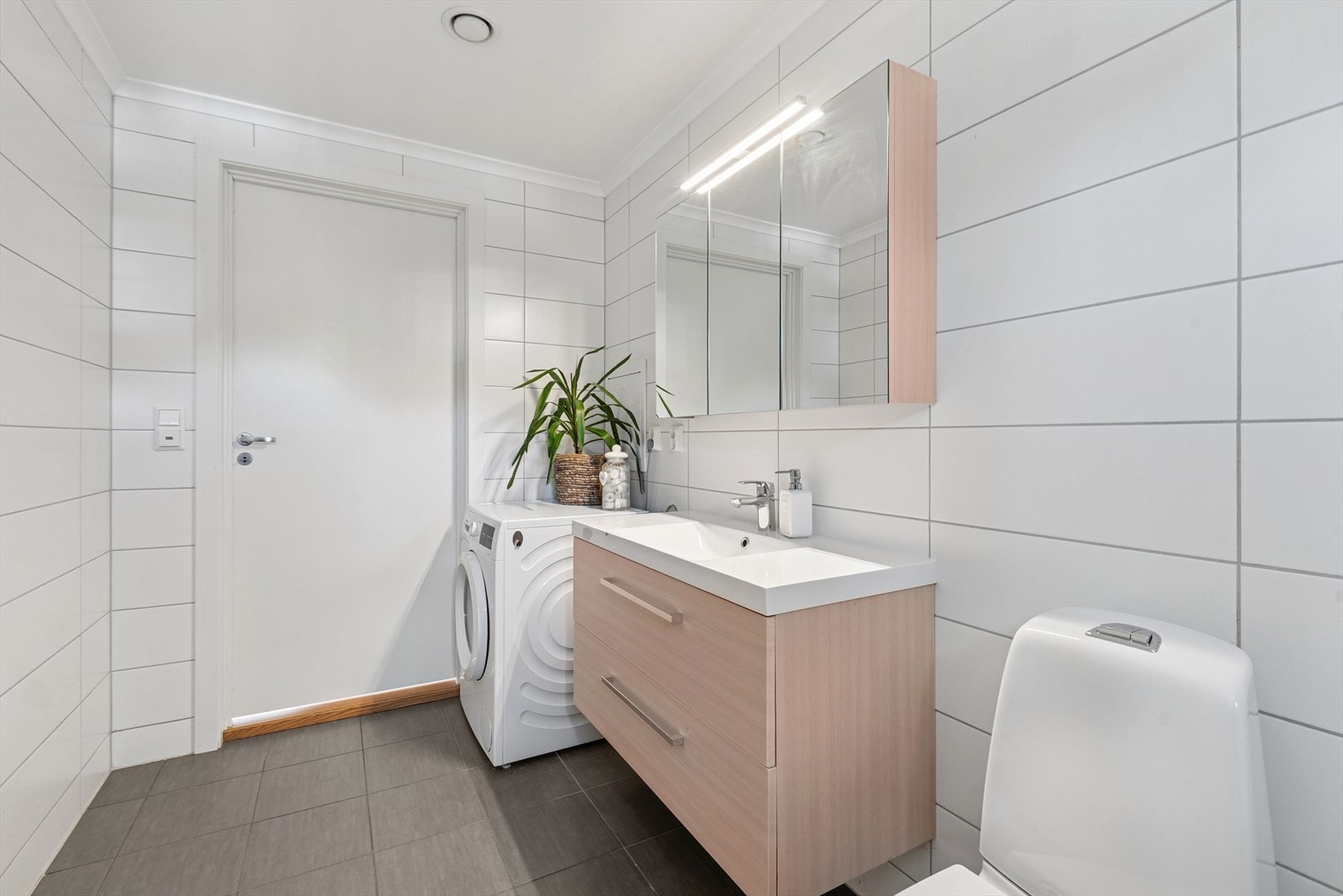 Det lekre badet fra 2018 har lyse tidløse fliser på gulv og vegger - opplegg for vaskemaskin - varmekabler og lekker innredning Galleribilde