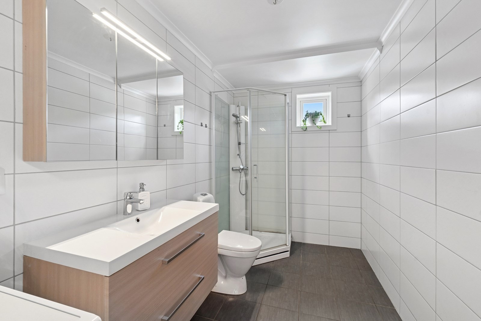 Badet er innredet med servantinnredning, dusjkabinett og toalett - varmekabler i det flislagte gulvet Galleribilde