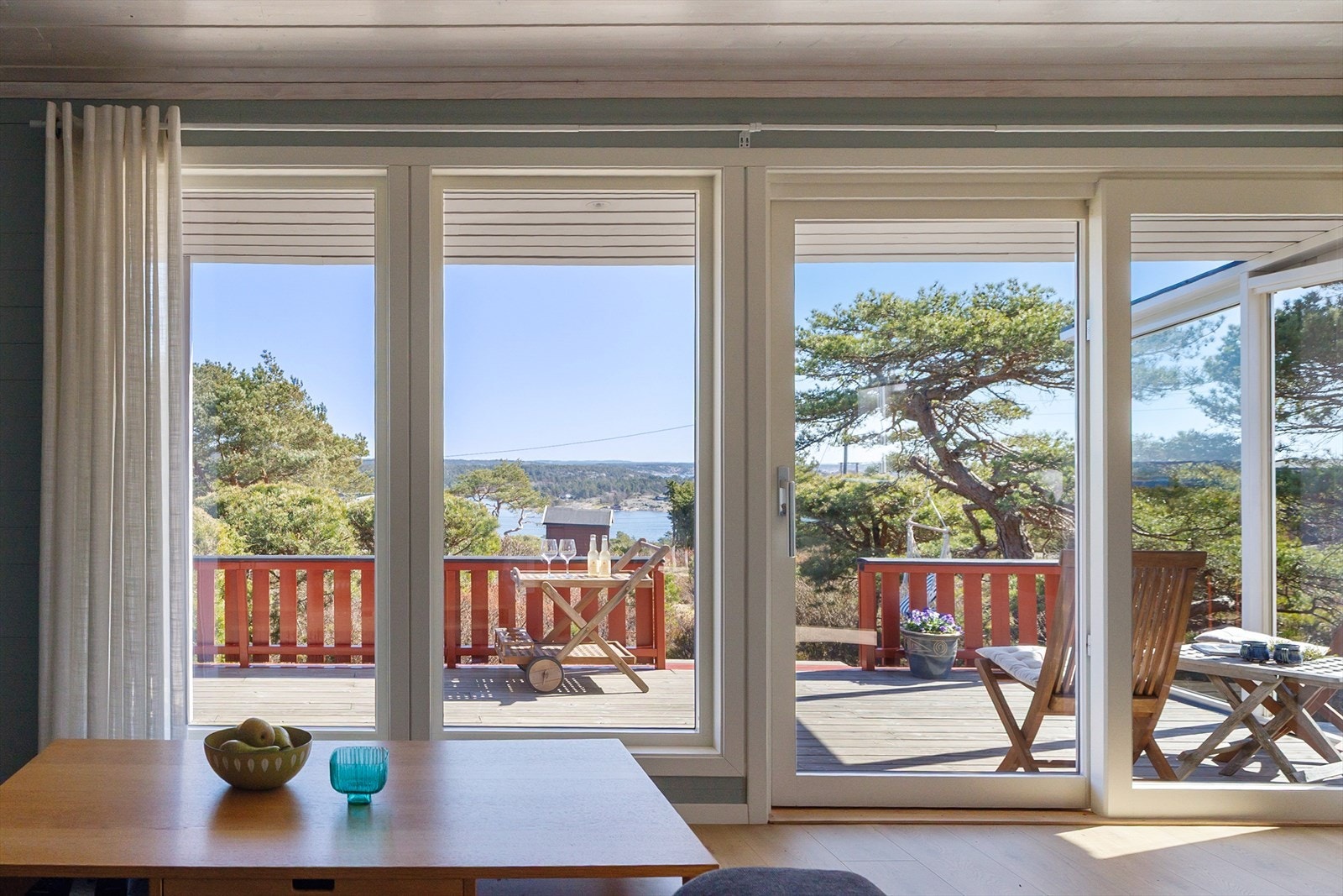 Store skyvedører fra stuen og ut mot delvis overbygd veranda med flott utsikt mot Asmaløy, Kirkøy og over til vindmøllene i Sverige. Galleribilde