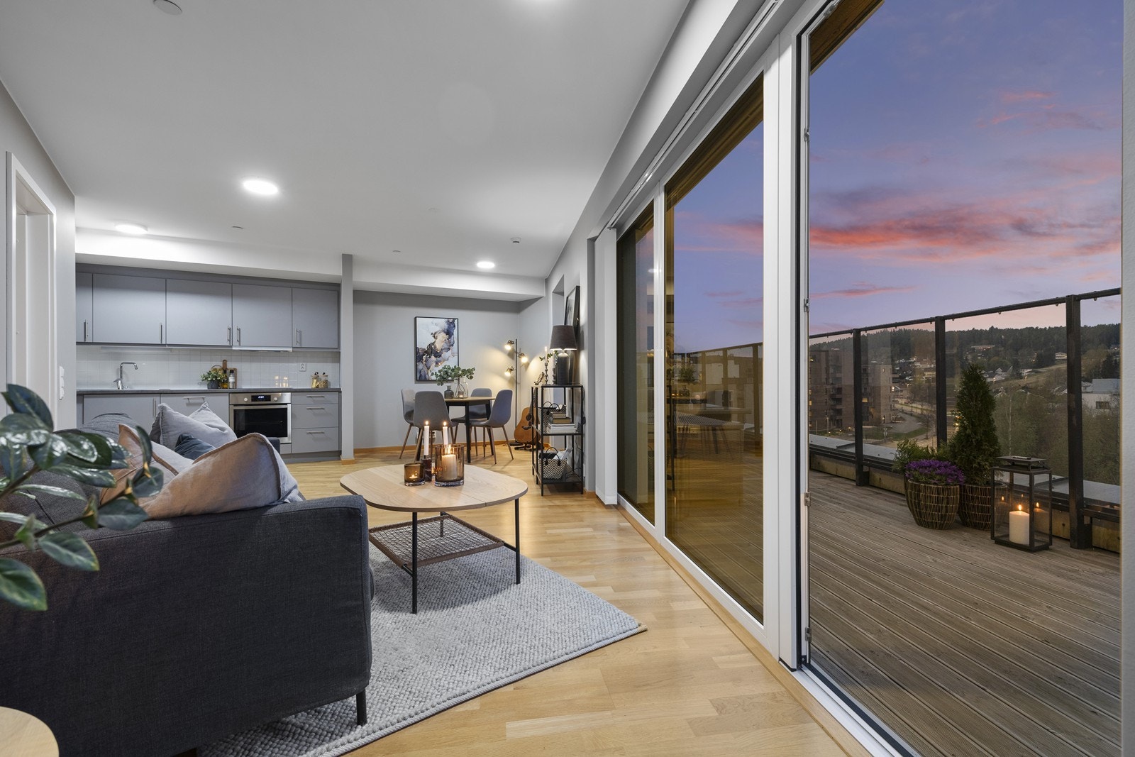 Lys og behagelig stue med vinduer og balkongdører som strekker seg fra gulv til tak. Galleribilde