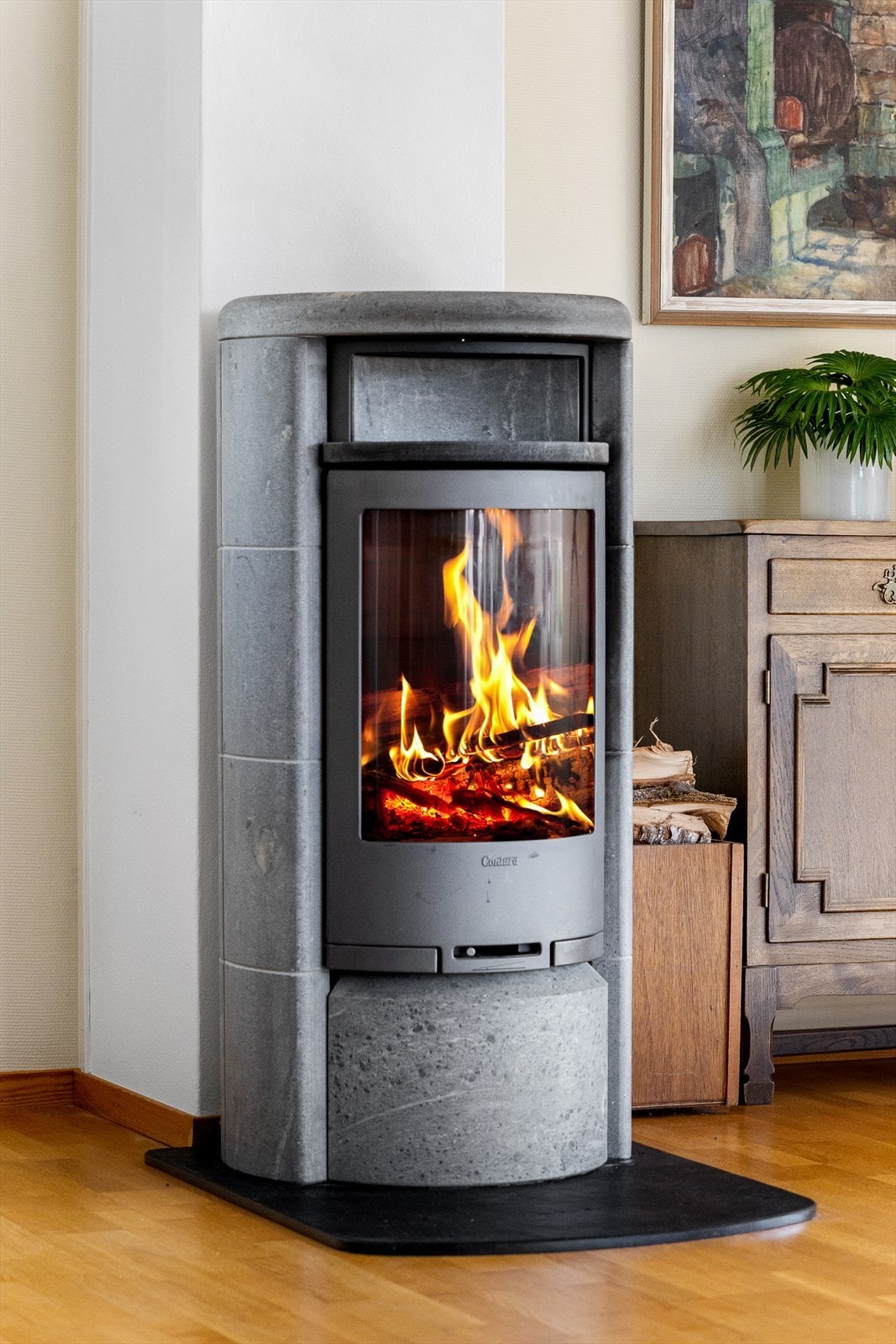 I stuen står en elegant peisovn som fungerer som et naturlig midtpunkt i rommet. Den kombinerer moderne design med funksjonell varme, og gir en lun og innbydende stemning gjennom hele året. Galleribilde