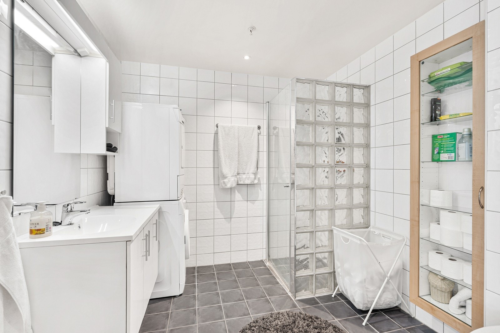 Badet er helfliset og har moderne innredning med vegghengt toalett, baderomsmøbel med servant og speil og dusjhjørne Galleribilde