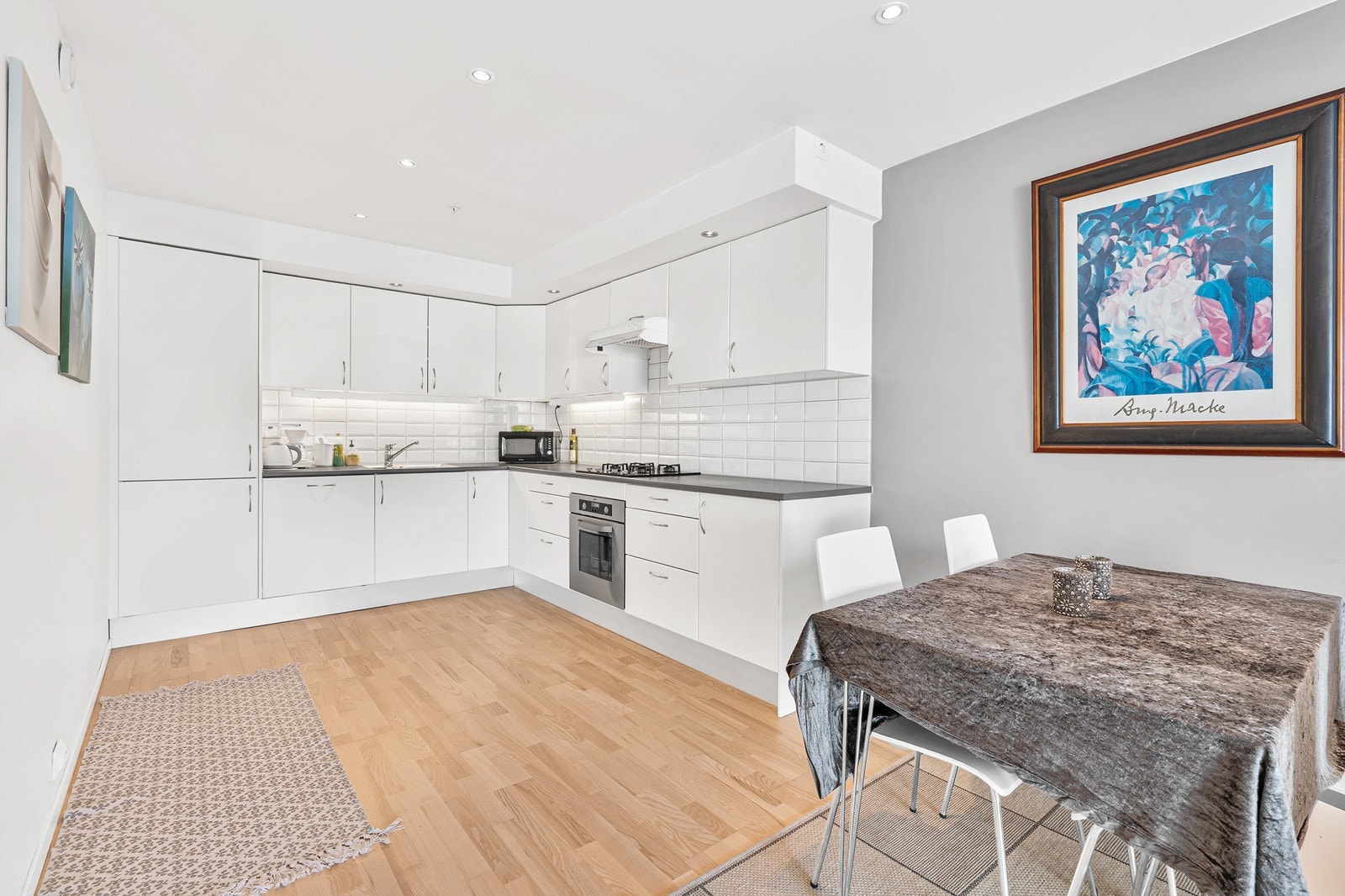 Kjøkkenet er pent og funksjonelt, med slette fronter i malt utførelse, laminat benkeplate og fliser mellom benk og overskap Galleribilde