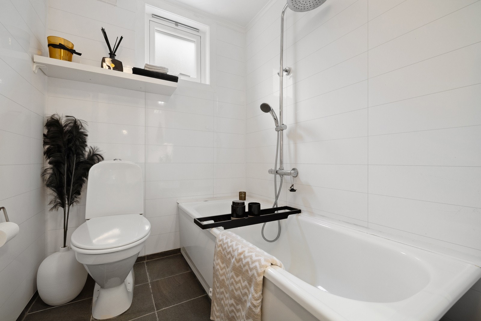 Badet har en tidløs stil med fliselignende våtromsplater på veggene og flotte gulvfliser (varmekabler). Badekar med dusjløsning og elektrisk avtrekksvifte. Galleribilde