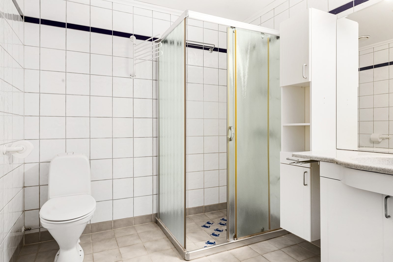Baderommet er utstyrt med innredning som inkluderer nedfelt servant med speil over, to høyskap som gir godt med oppbevaringsplass, samt klosett. Det er opplegg for vaskemaskin og et dusjhjørne med god plass. Galleribilde