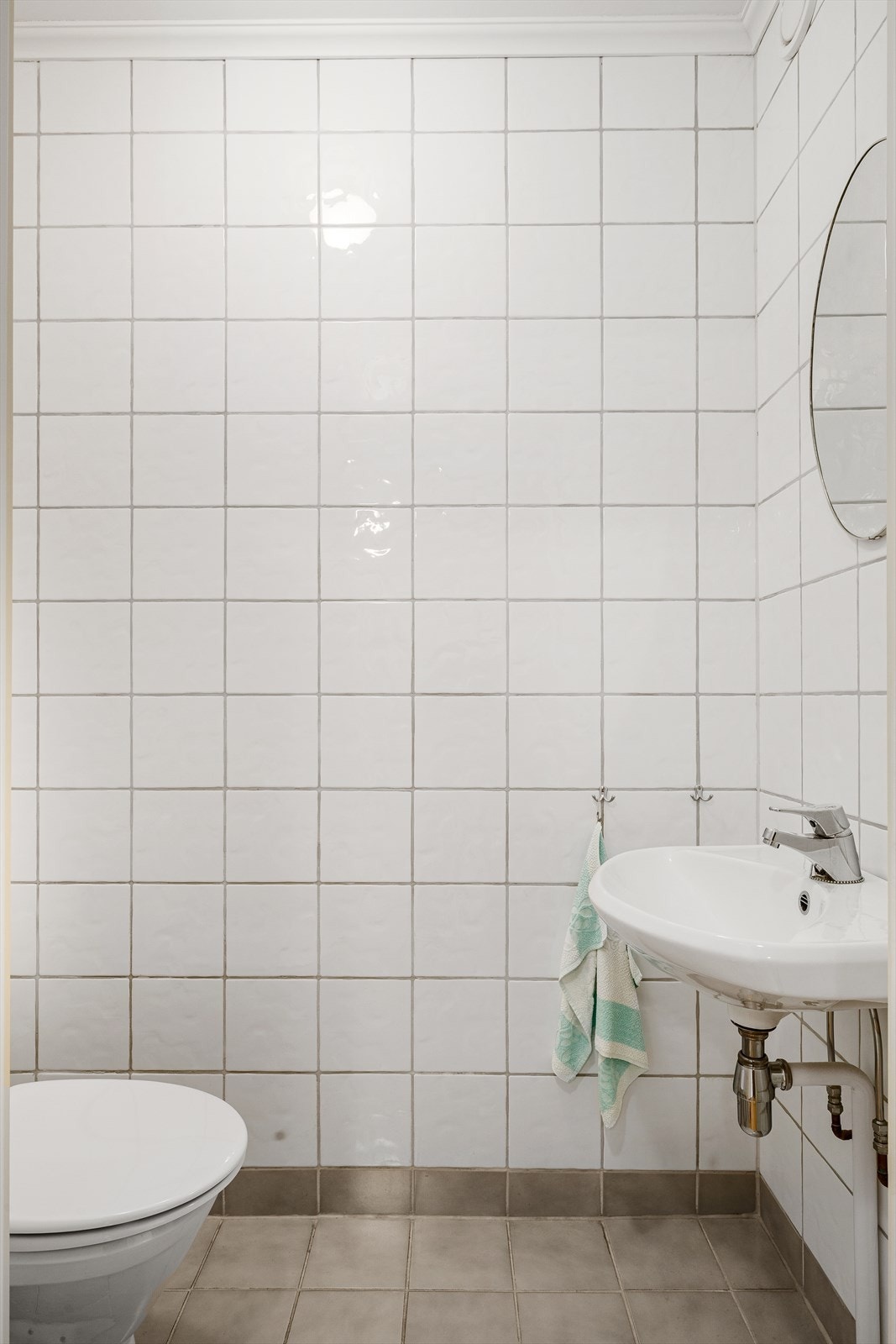 Toalettrom med flis på gulv og vegger. Innredet med servant, speil og klosett. Galleribilde