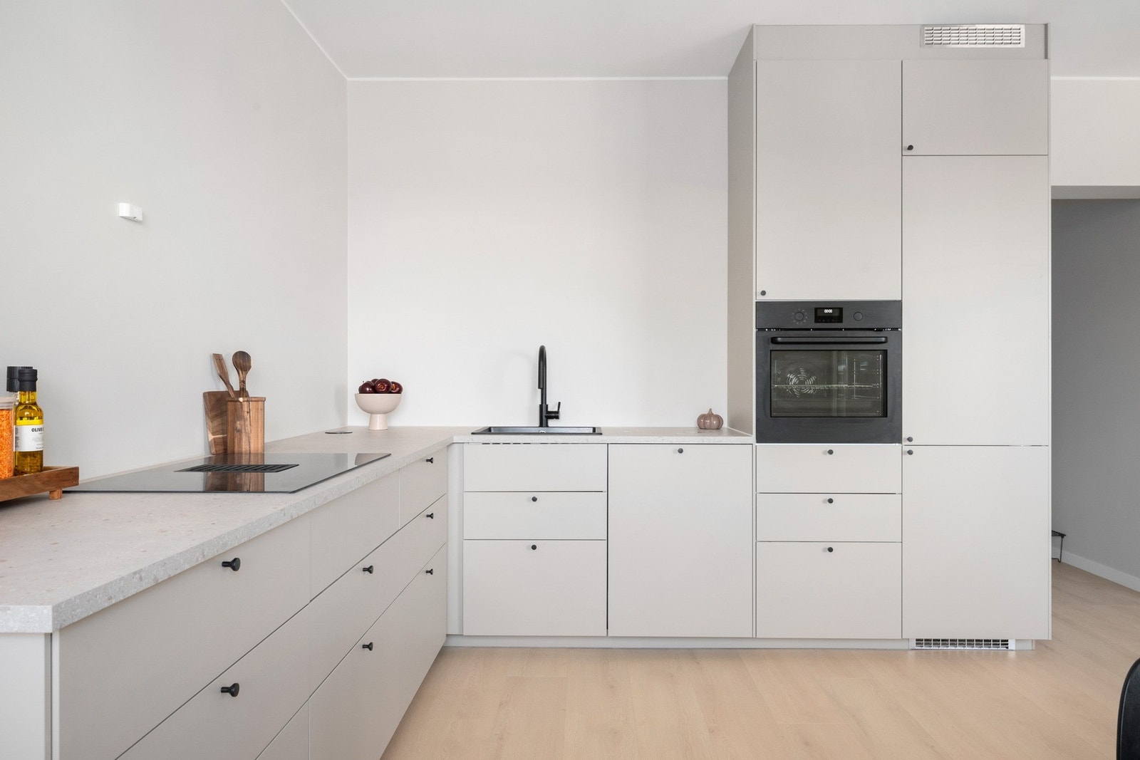 Kjøkkeninnredning fra 2025 med glatte, laminerte fronter og benkeplate i laminat. Integrert kjøl/fryseskap, oppvaskmaskin, stekeovn og platetopp. Kullfilterventilator i kokesone Galleribilde