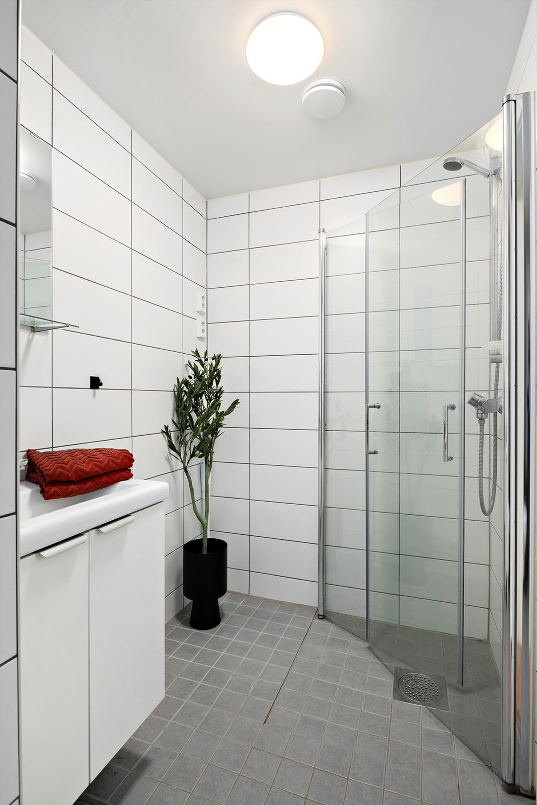 Badet inneholder servantskap med speil, innfellbare dusjdører, vegghengt toalett og opplegg for vaskemaskin Galleribilde