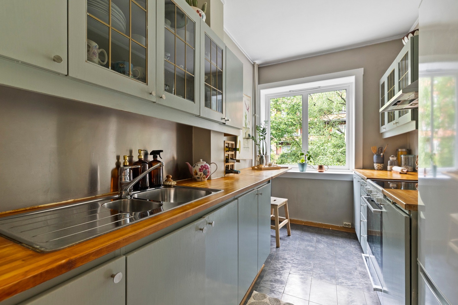 Kjøkkenet er utstyrt med vask på god størrelse og rikelig med benkeplass. De lyseblå overskapene med glassfronter gir et sjarmerende preg Galleribilde