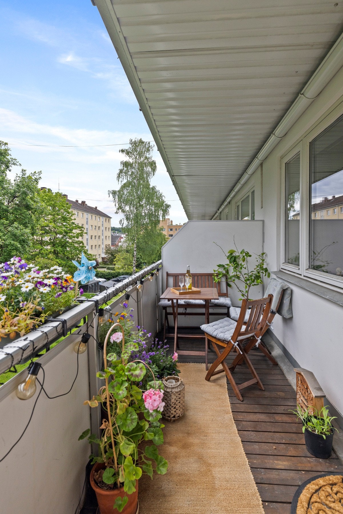 Perfekt for lek og avslapning i det fri. En komfortabel sitteplass på balkongen, omringet av vakre blomster og planter Galleribilde