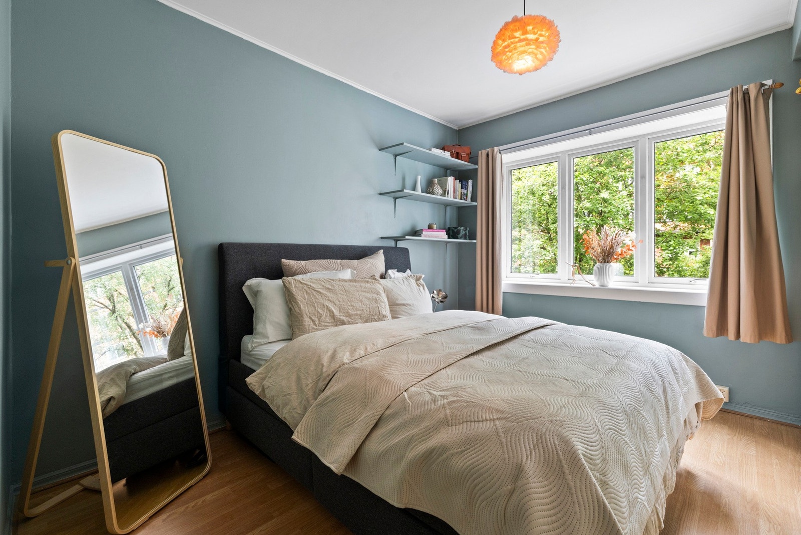 Sjarmerende soverom med utsikt til grønne trær. Smart oppbevaring med åpne hyller over sengen Galleribilde