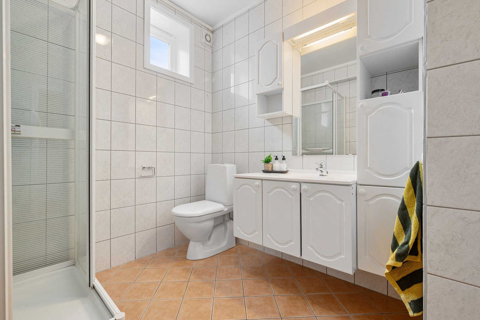 Badet inneholder servantinnredning, toalett og dusjkabinett Galleribilde