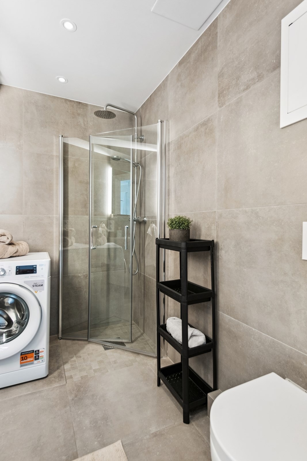 Dusjhjørnet har glassdører som enkelt kan skyves inn mot veggen i rommet, opplegg for vaskemaskin og god plass til ekstra kommode for oppbevaring. Galleribilde