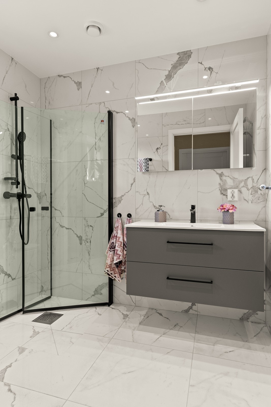 Bad i 2. etasje er helfliset med elegante marmorfliser på både gulv og vegger, og har slett malt himling med spotter. Her finner du grå baderomsinnredning med skuffer og heldekkende servant. Galleribilde