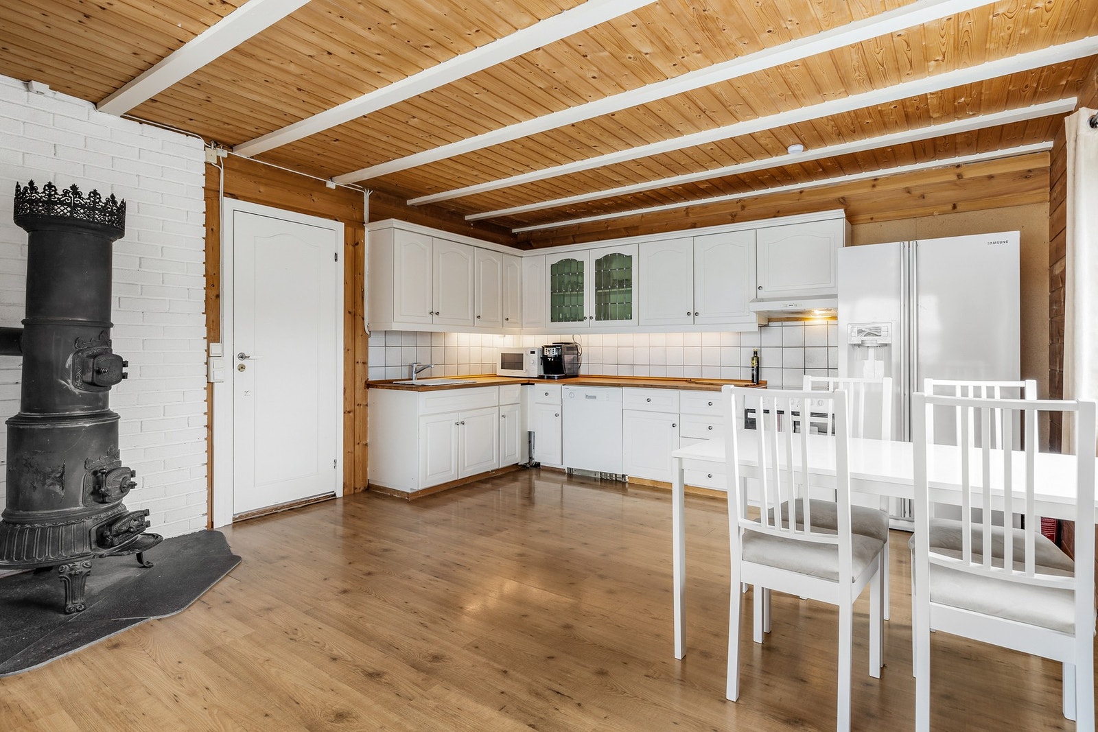 Innredningen har frittstående hvitevarer, herunder kjøl/fryseskap, oppvaskmaskin, og komfyr Galleribilde