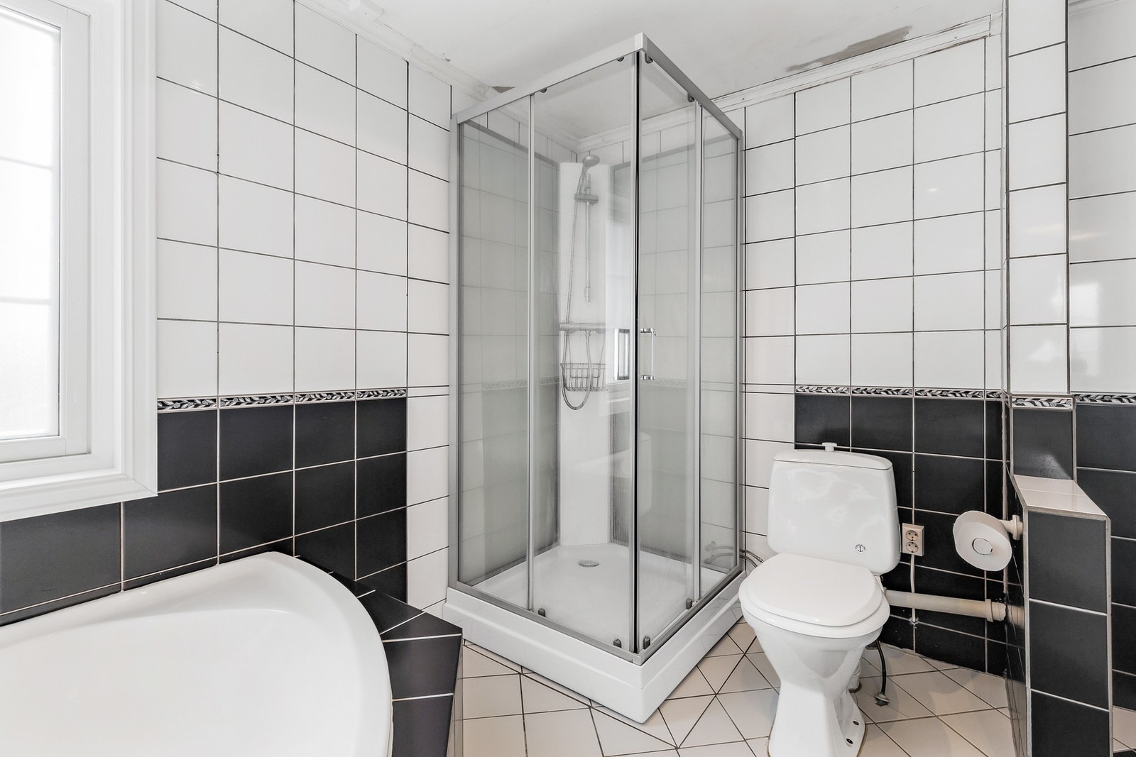 Badet er utstyrt med gulvstående toalett, dusjkabinett, badekar og servantinnredning Galleribilde