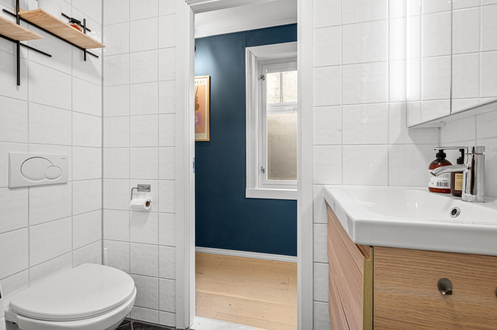 Badet har vegghengt klosett og servant med skuffer, samt speilskap med belysning og oppbevaring Galleribilde