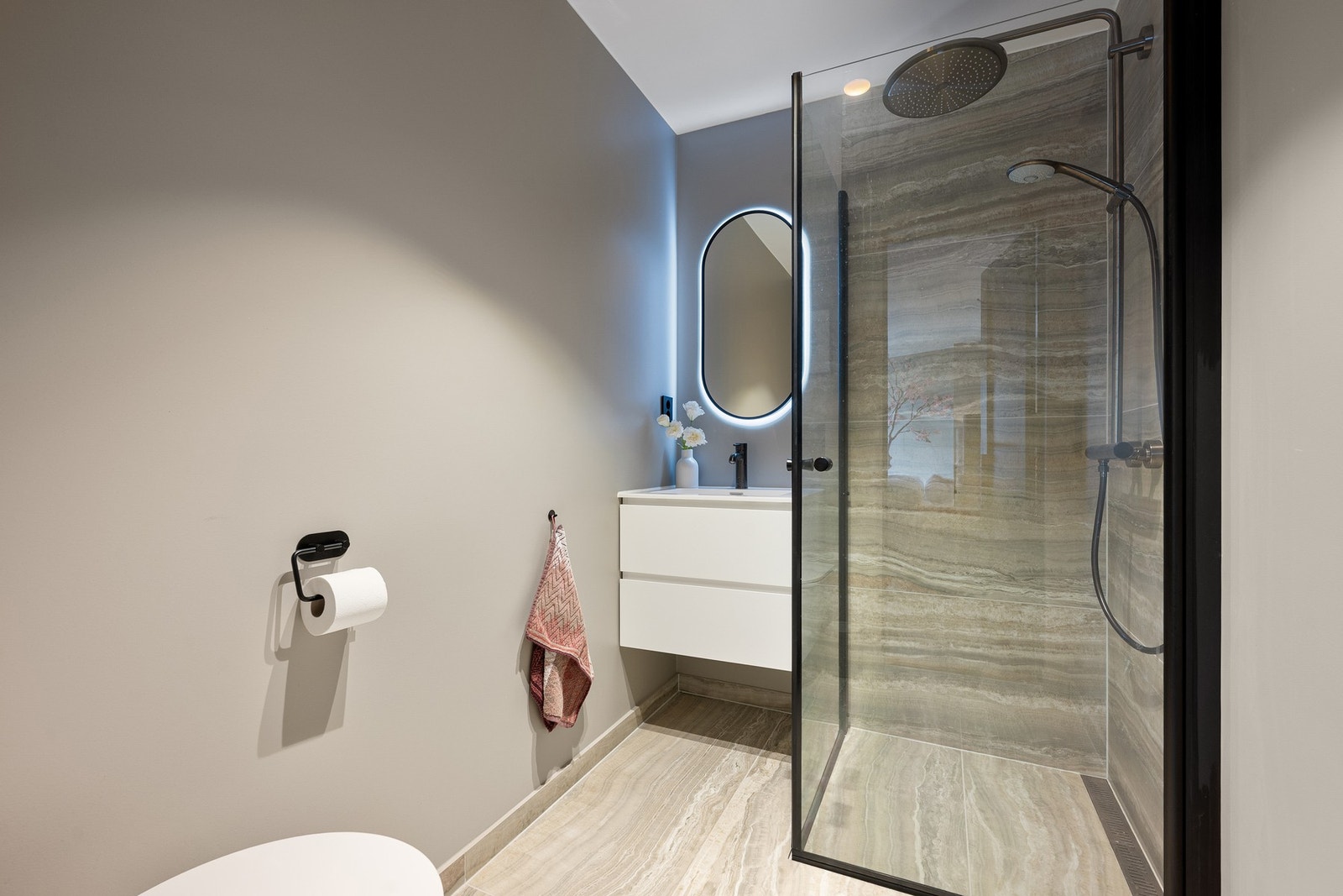 Lekkert en-suite bad med 120x60 cm italienske travertin porselensfliser fra Norfloor, skjult sisterne og servant med skuffer. Galleribilde