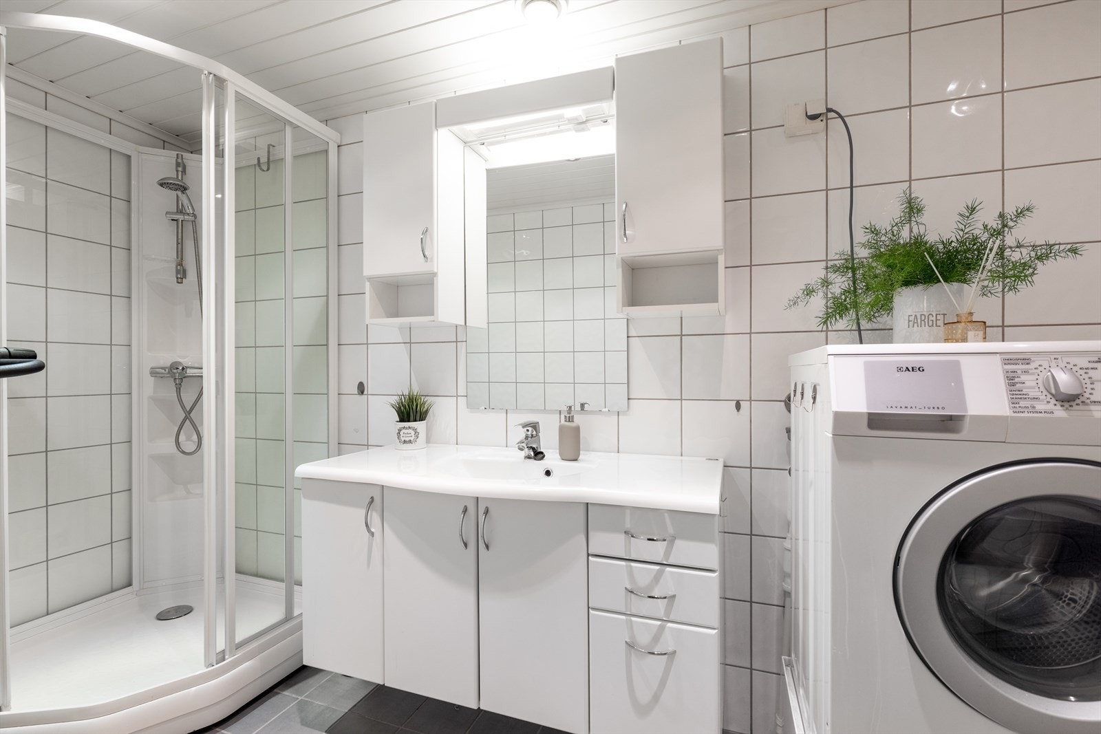 Badet har også toalett og dusjkabinett, samt opplegg vaskemaskin. Romslig servantinnredning, samt speil med sideskap og overlys. Galleribilde