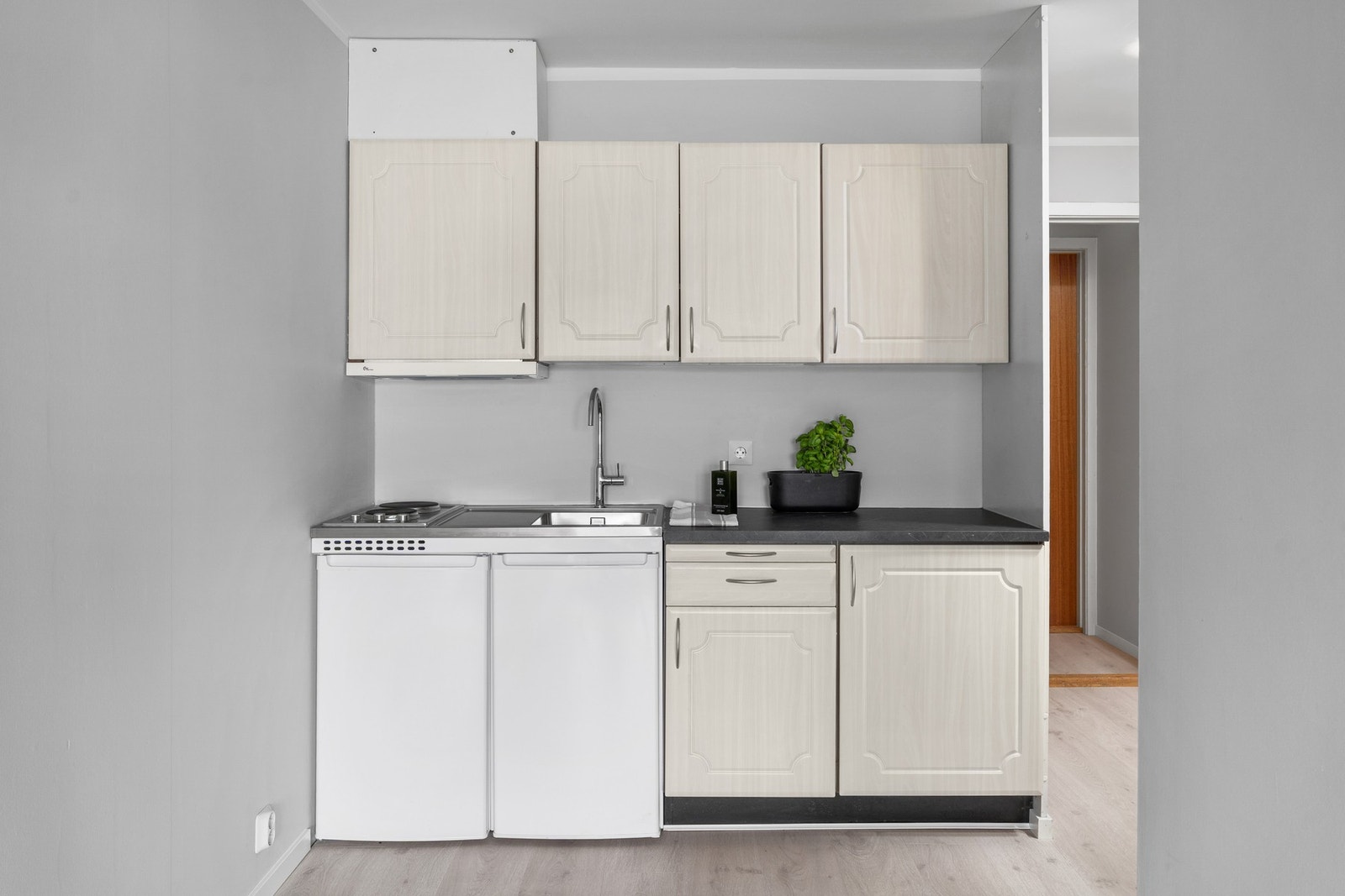 Praktisk minikjøkken utstyrt med integrert kjøleskap og platetopp. Galleribilde