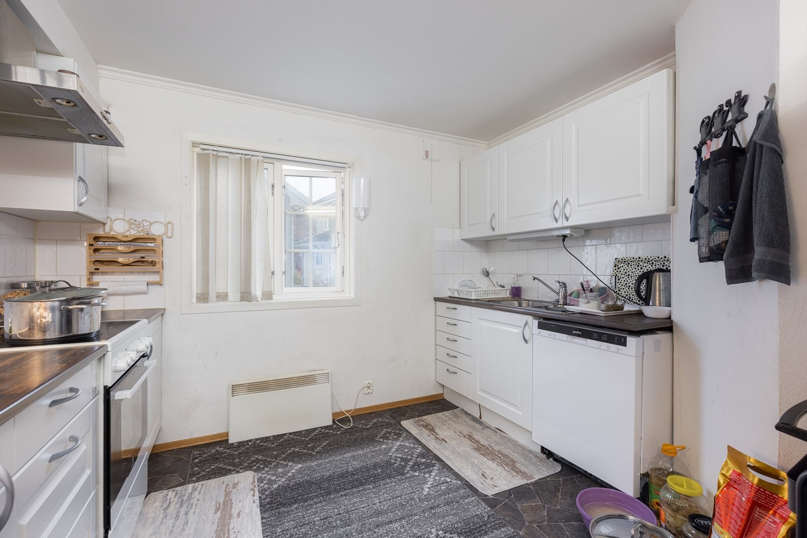 Benkeplater har laminerte flater og det er flis på vegg mellom over- og underskap. Opplegg og plass til frittstående kjøleskap, oppvaskmaskin og komfyr. Galleribilde