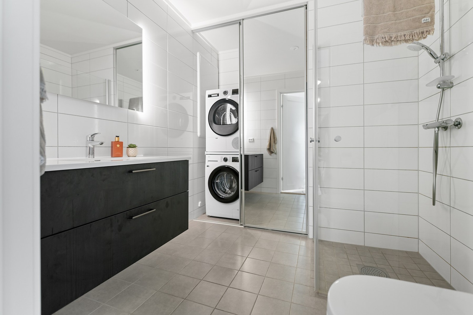 Delikat og moderne bad med fliser på gulv og vegger. Opplegg for vaskemaskin. Galleribilde