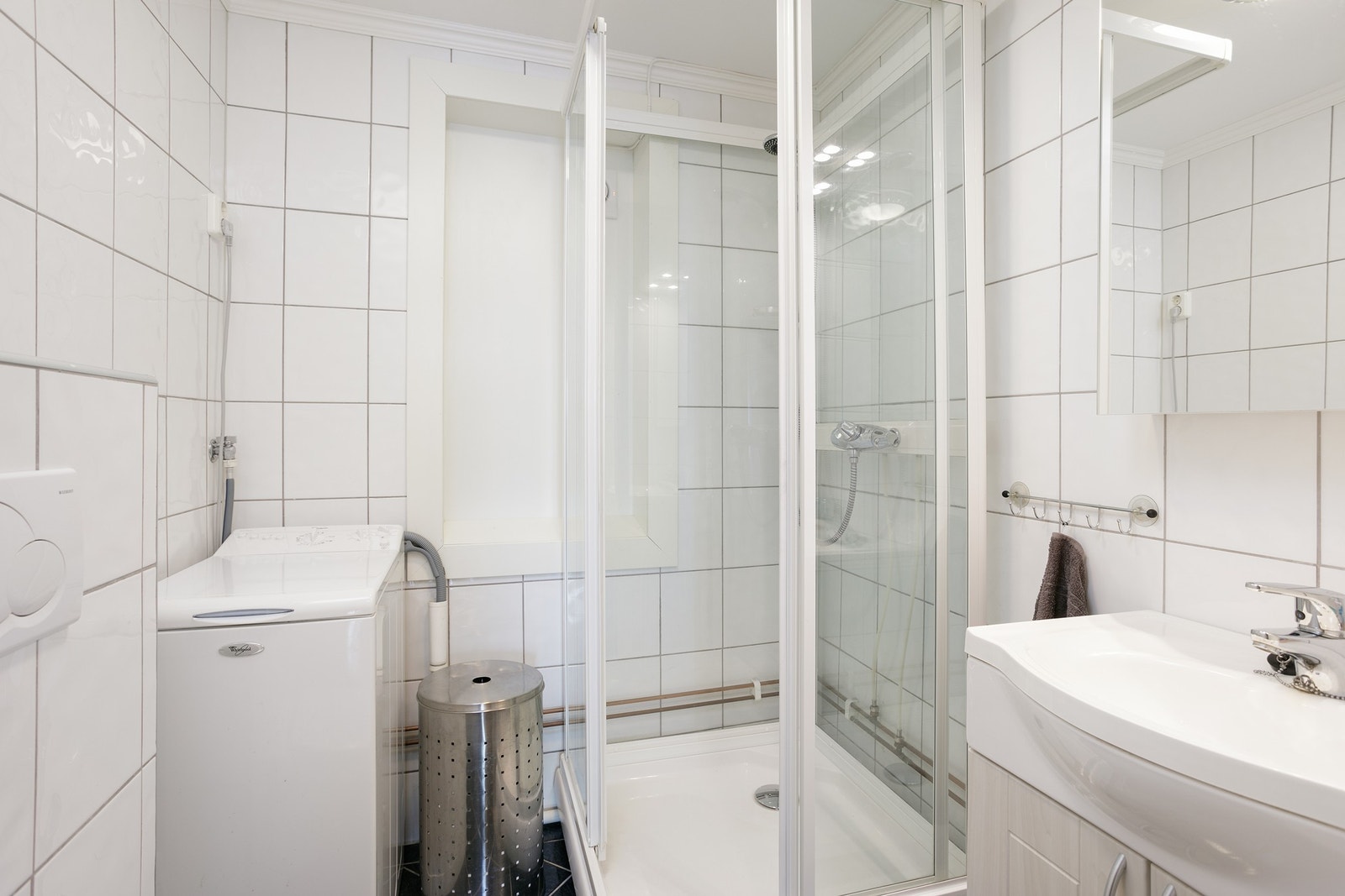 Badet er innredet med dusjkabinett, vask og vaskemaskin Galleribilde