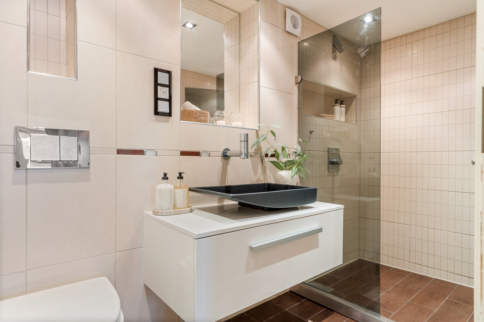 Romslig, helfliset baderom med dusjnisje, vegghengt toalett, skuffeseksjon og speil. Varmekabler i gulv. Galleribilde