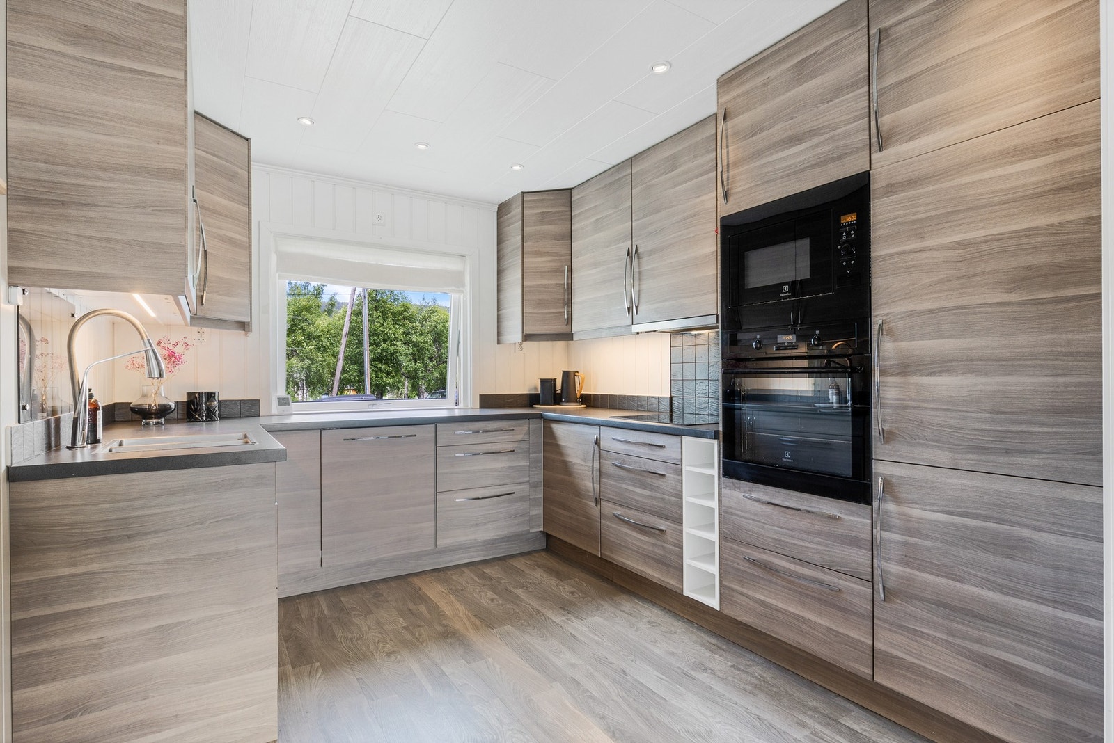 Lekkert kjøkken som har rikelig med skap- og benkeplass og integrerte hvitevarer Galleribilde