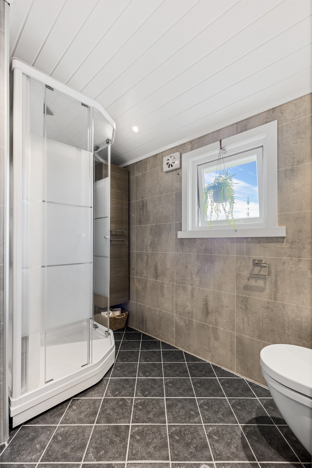 Baderommet er innredet med dusjkabinett, vegghengt toalett, servant med underskuffer, vegghengt speilskap Galleribilde