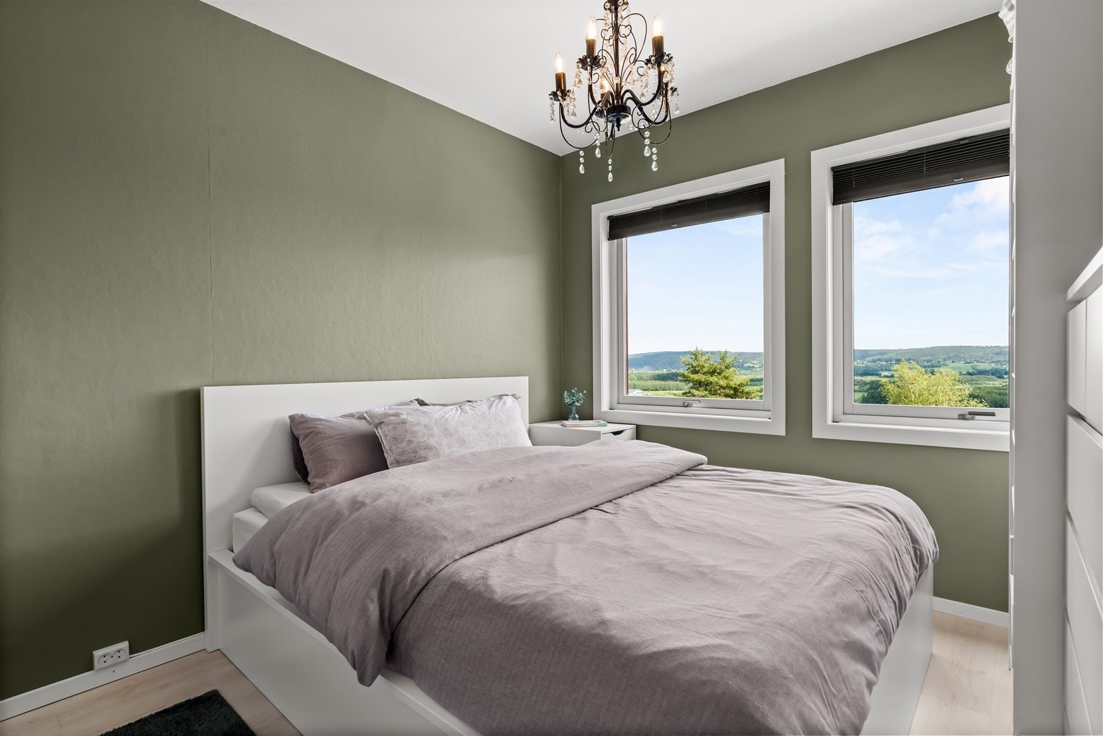 Leiligheten har et romslig soverom malt i en lun og delikat grønnfarge. Galleribilde