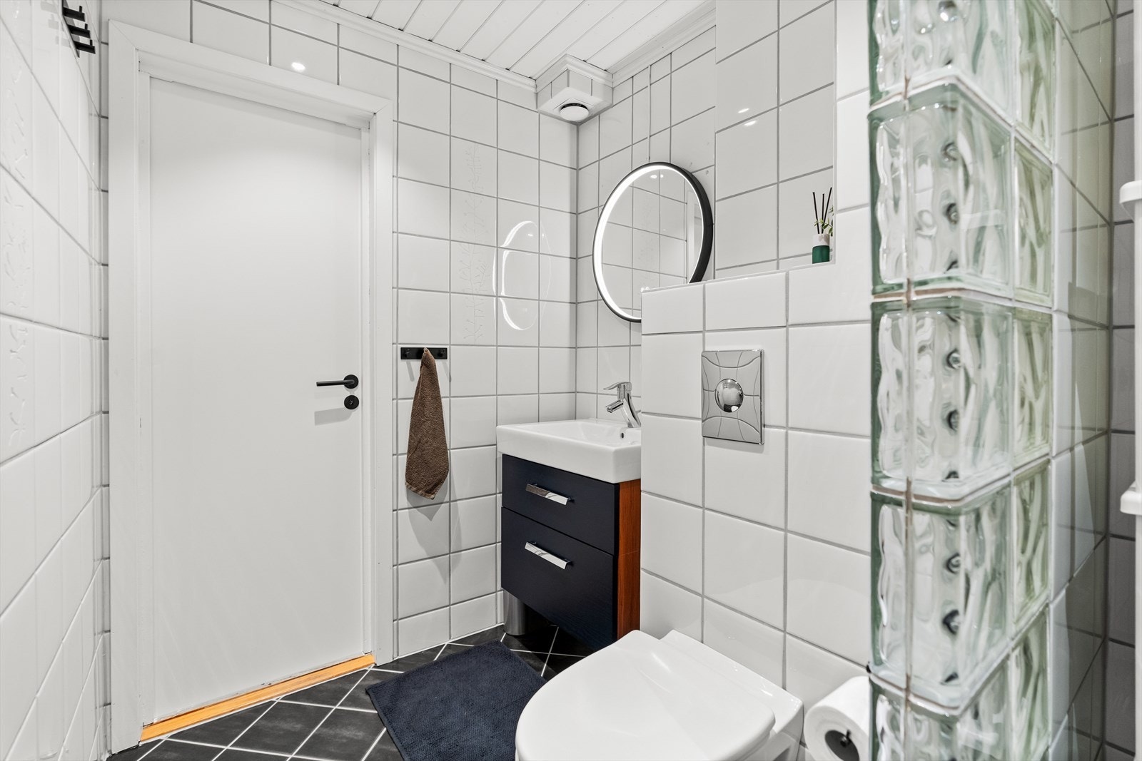 Innredningen består av dusjkabinett, servant med underskuffer, speil med integrert belysning, vegghengt toalett og opplegg for vaskemaskin. Galleribilde